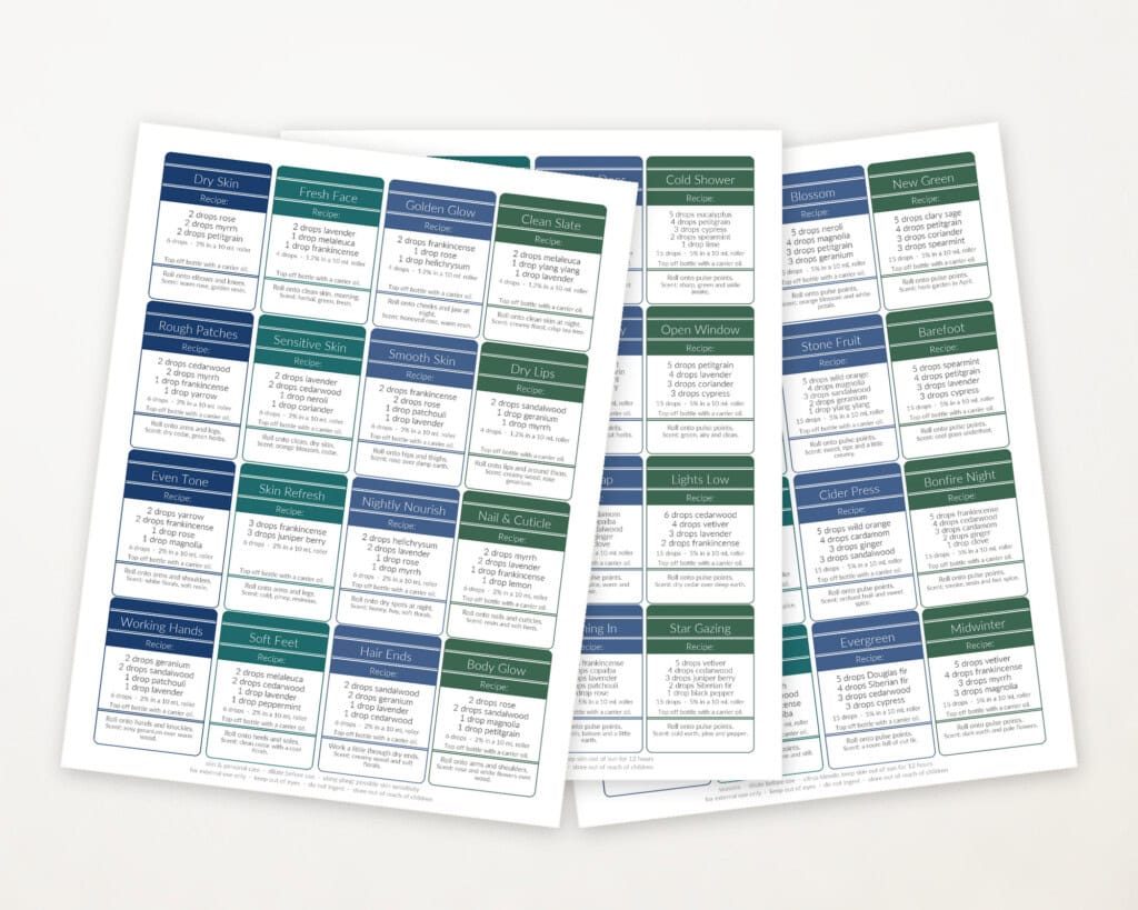 Six pages of essential oil roller bottle recipe labels spread out on a table.