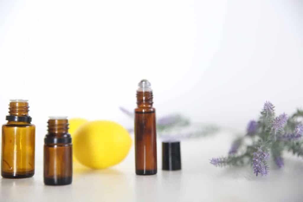 Essential oil bottles on white table with fresh lemons and lavender.
