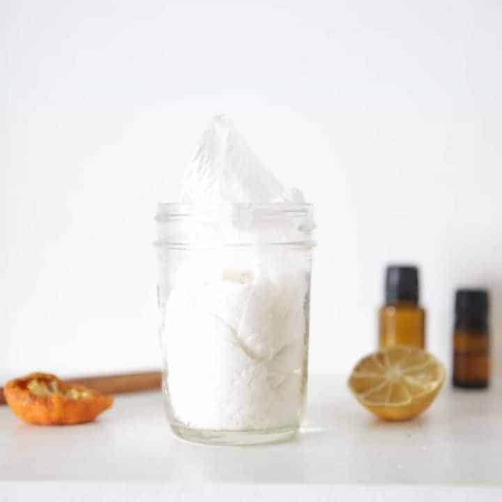 Homemade cleaning wipes in a storage mason jar on a white marble table.