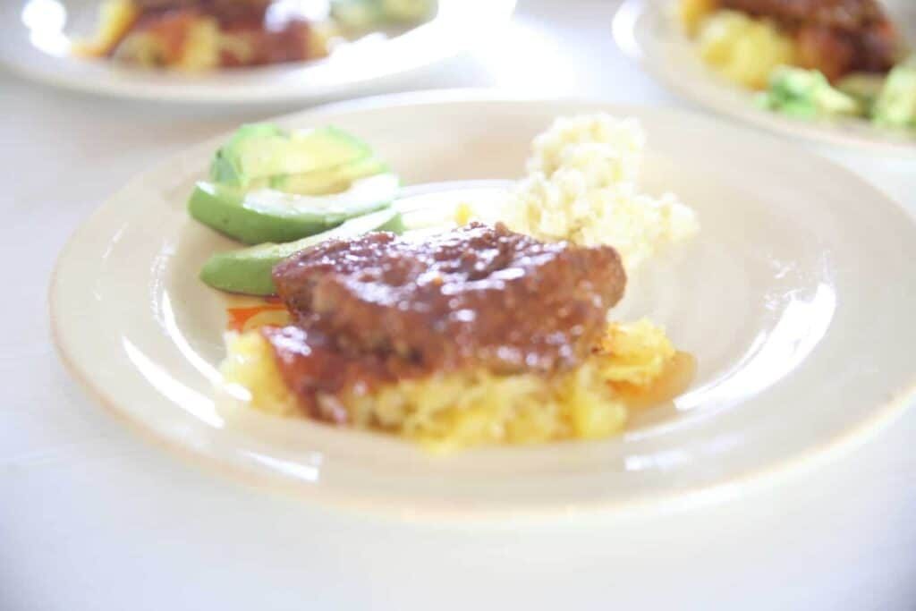 Spaghetti squash with red sauce, avocado and sauerkraut on plate.