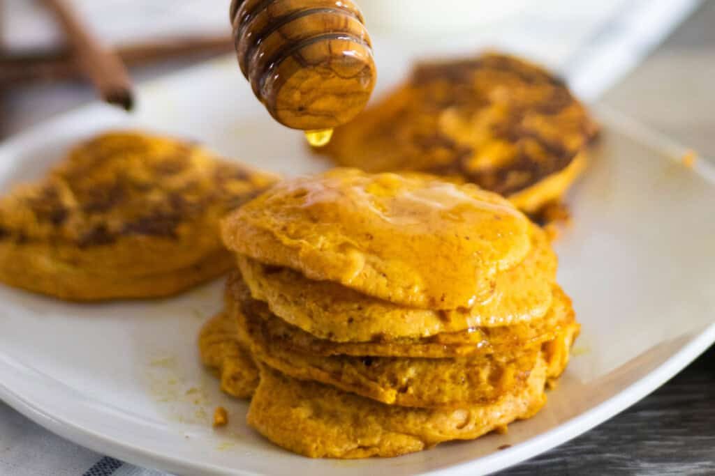 A white plate with stacks of pumpkin pancakes on it.