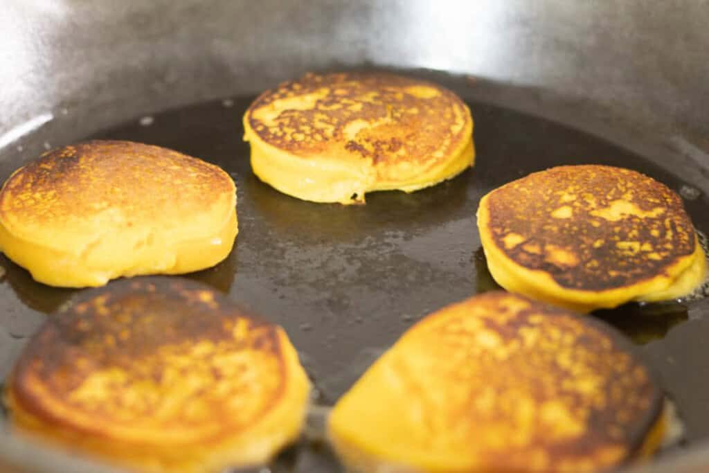 Frying pumpkin pancakes in a cast iron skillet.
