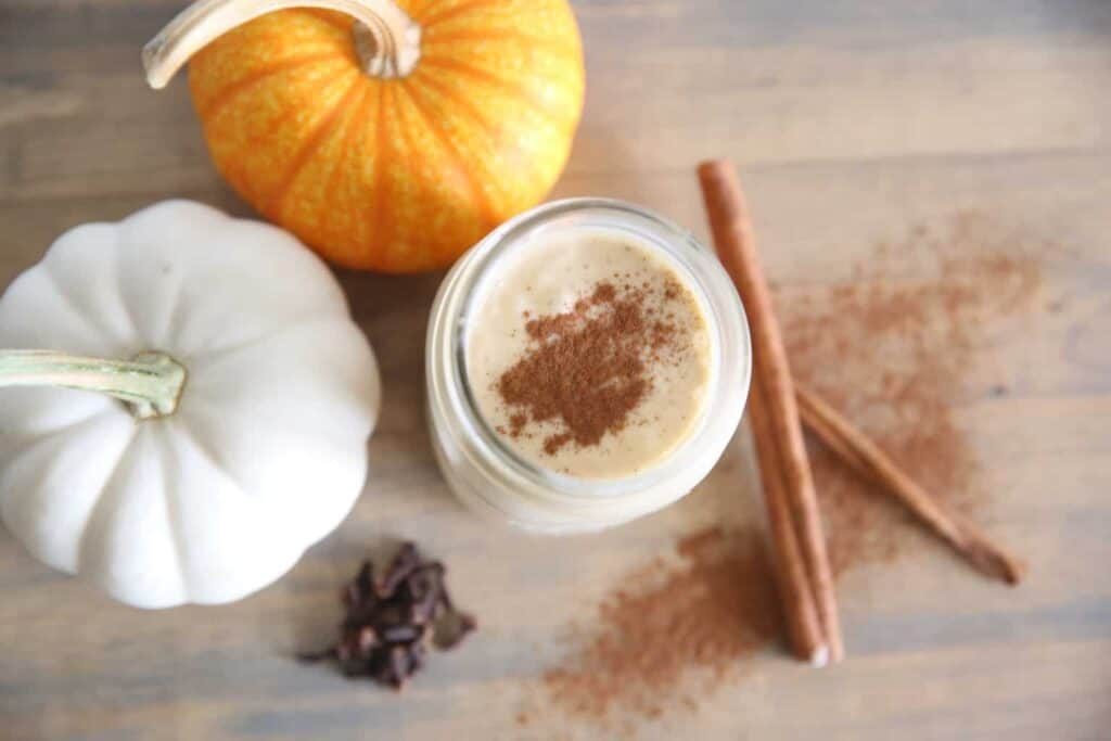 pumpkin spice smoothie with pumpkins and cinnamon sticks.