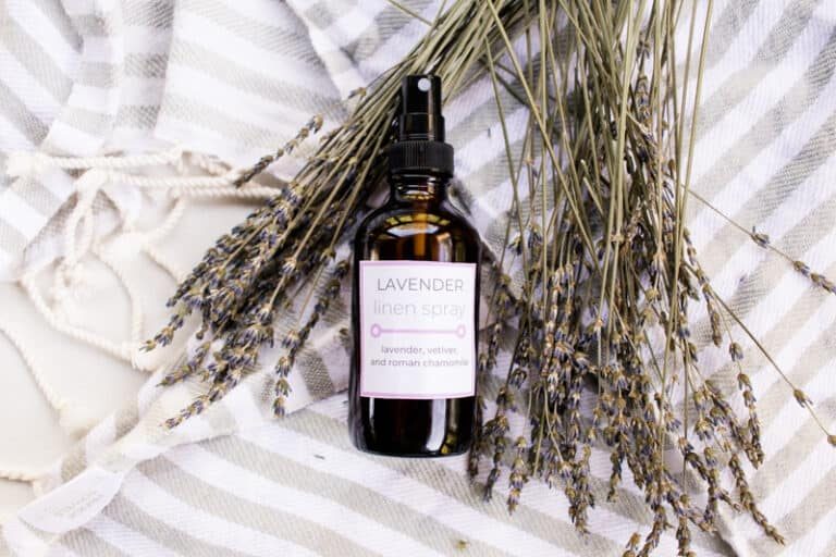 Lavender linen spray bottle with lavender sprigs nearby.