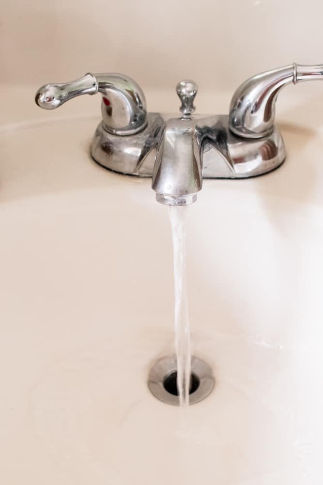 A bathroom faucet with the water running.