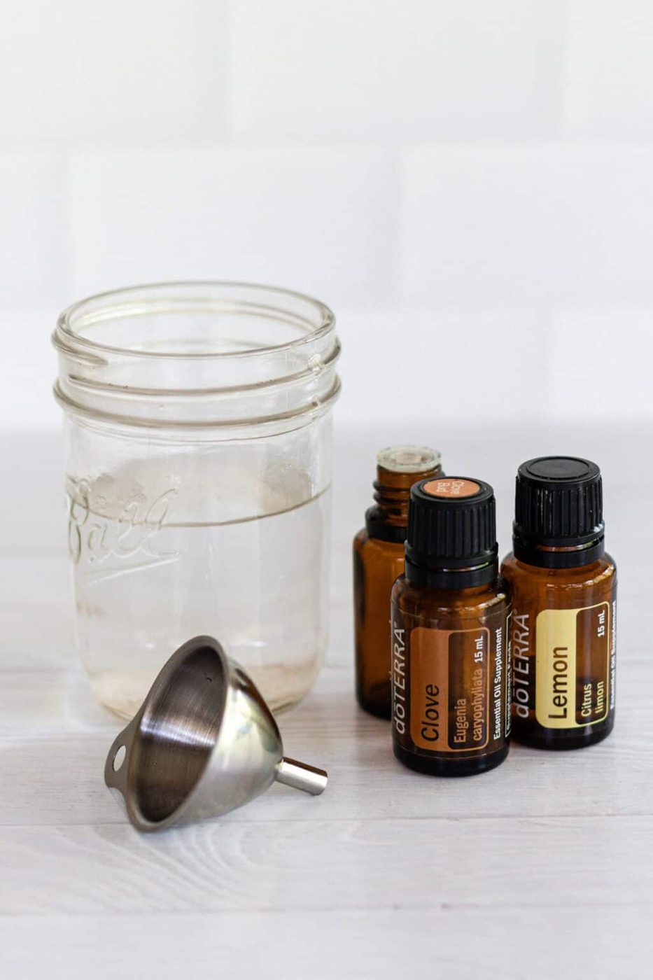 Ingredients for ant repellent: essential oils and water with a metal funnel.
