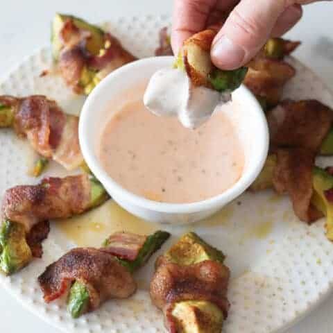 Bacon wrapped avocado fry dipped in spicy paleo dip.