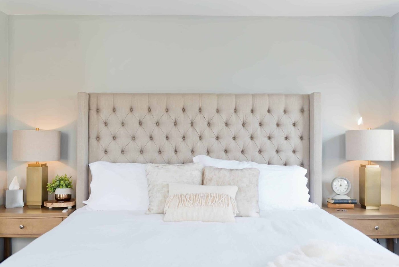 A bed with a large beadboard and bedside lamps turned on.