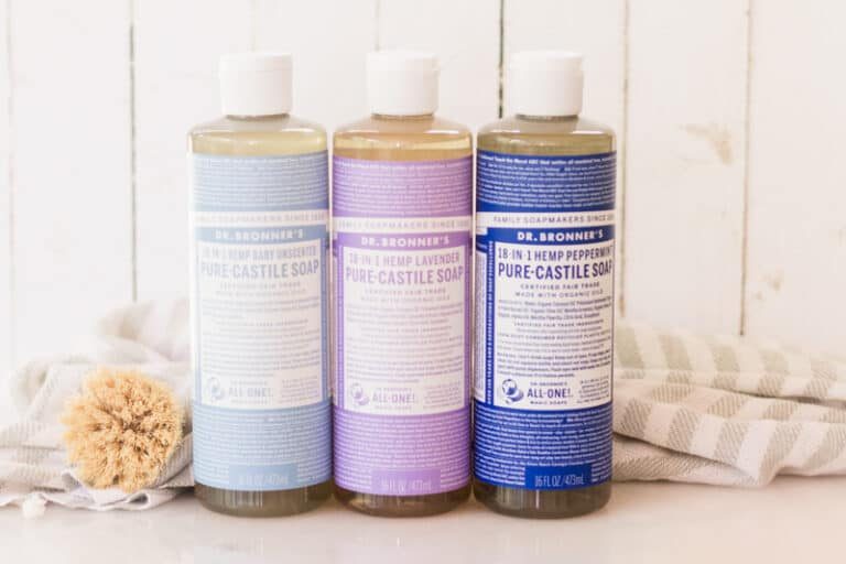 Bottles of castile soap, one light blue, one purple, and one dark blue.