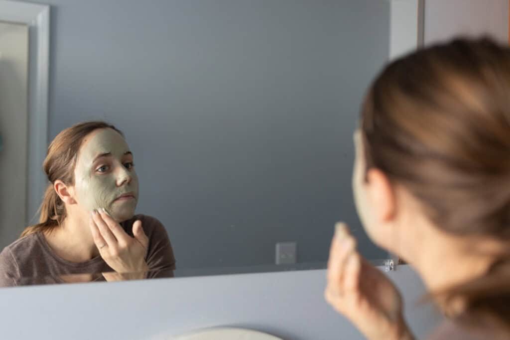 The author applying a face mask in her bathroom mirror.