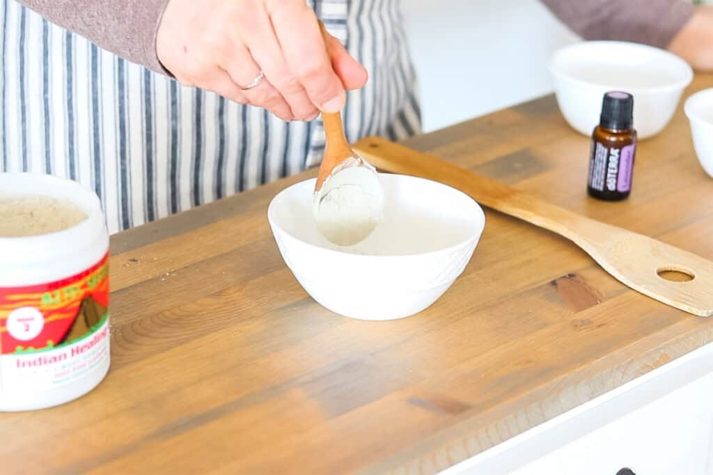 Adding bentonite clay to a small bowl.