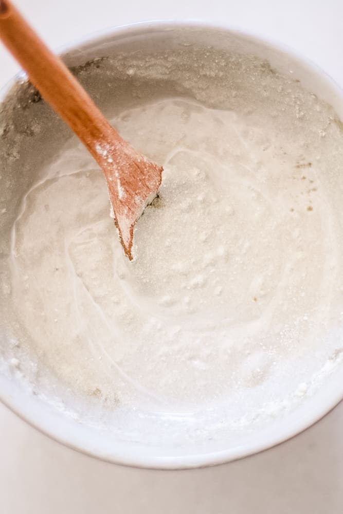 Bentonite clay balm in small bowl with wooden spoon.