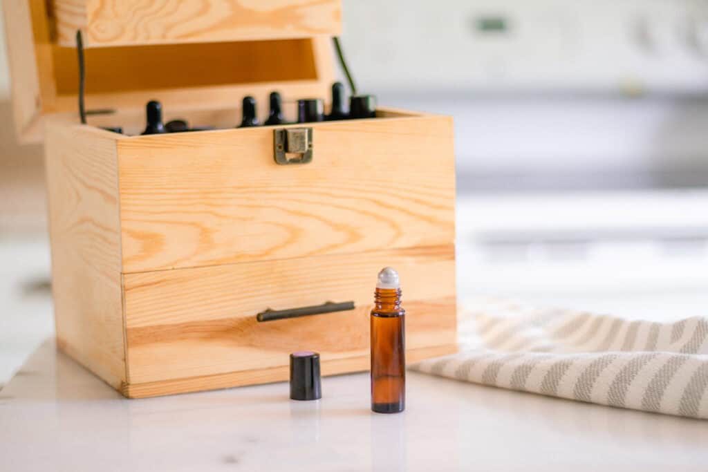 Wooden essential oil storage box with an open roller bottle of bergamot in front of it.