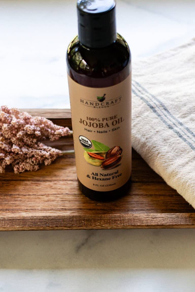 Jojoba oil sitting on a wooden tray.
