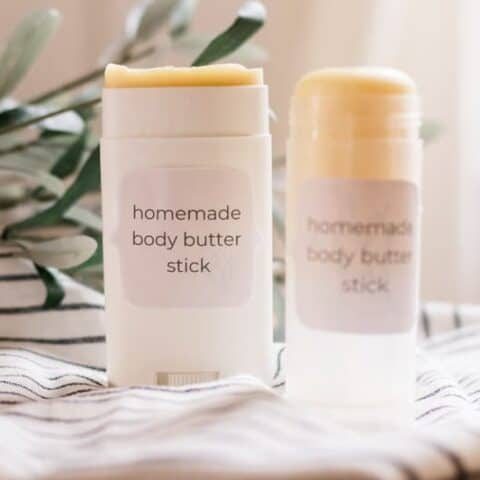 Two body butter sticks on white and black stripe towel.