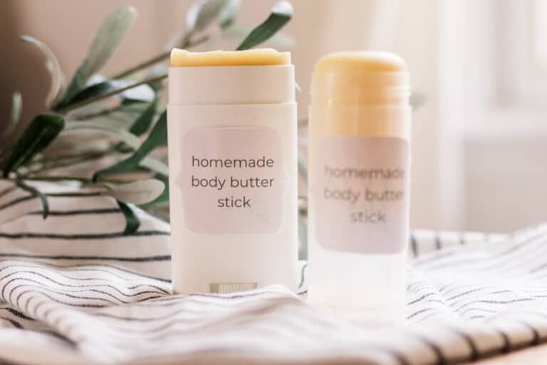Two body butter sticks on white and black stripe towel.