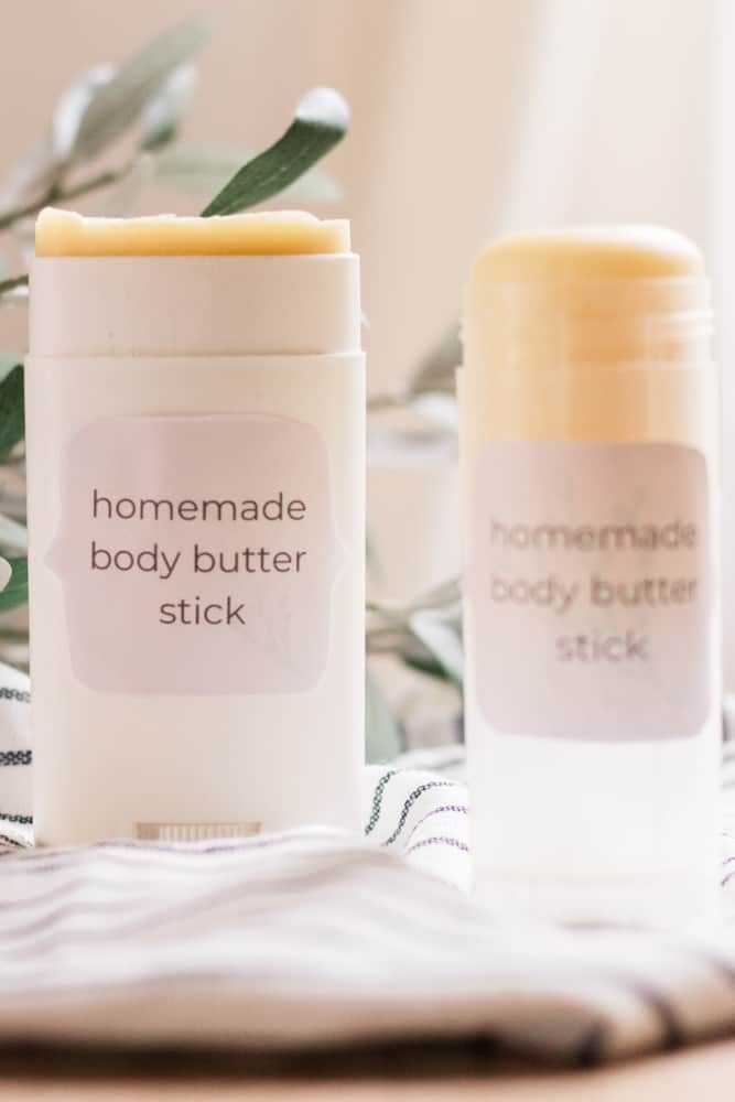 Lotion bar sticks on towel with greenery behind them.