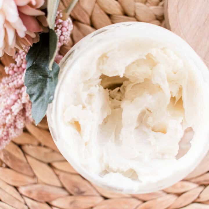Natural body cream in a open top glass storage jar.