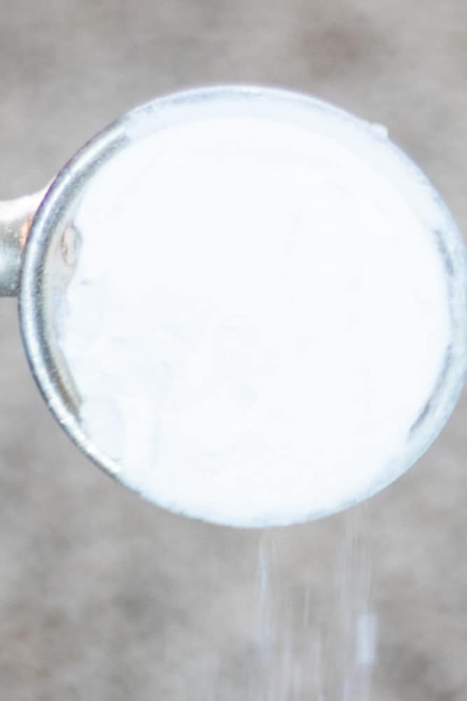 Pouring Baking soda onto carpet stain.