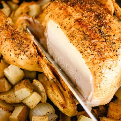 Slicing a roast chicken with a sharp knife.