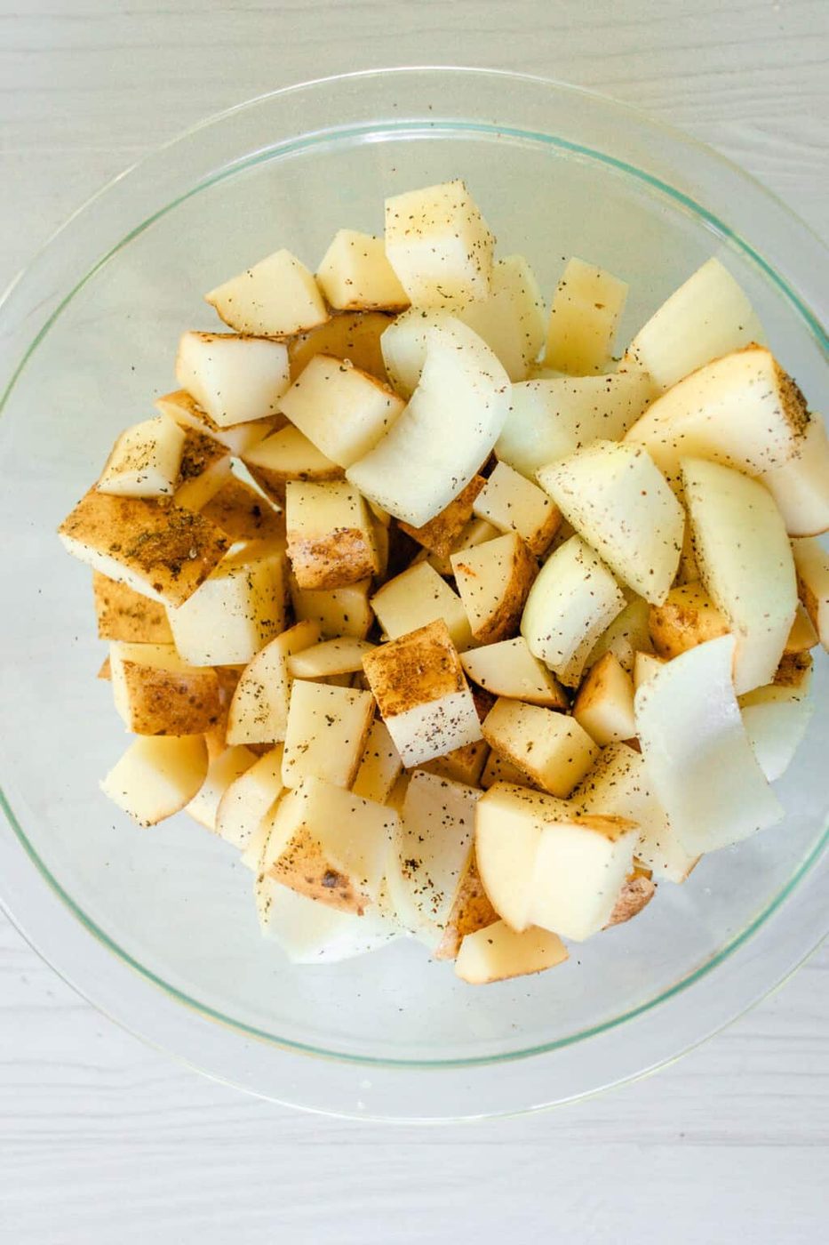 Dice the potatoes and onions and toss them in a small bowl with avocado oil, salt, and pepper.