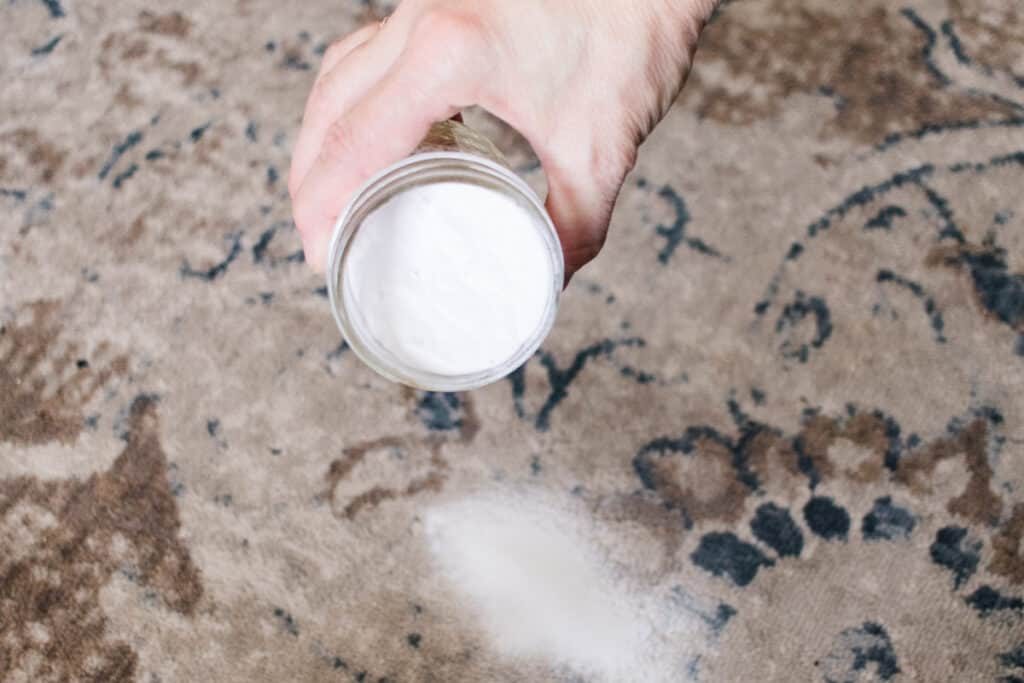Adding baking soda to a carpet.