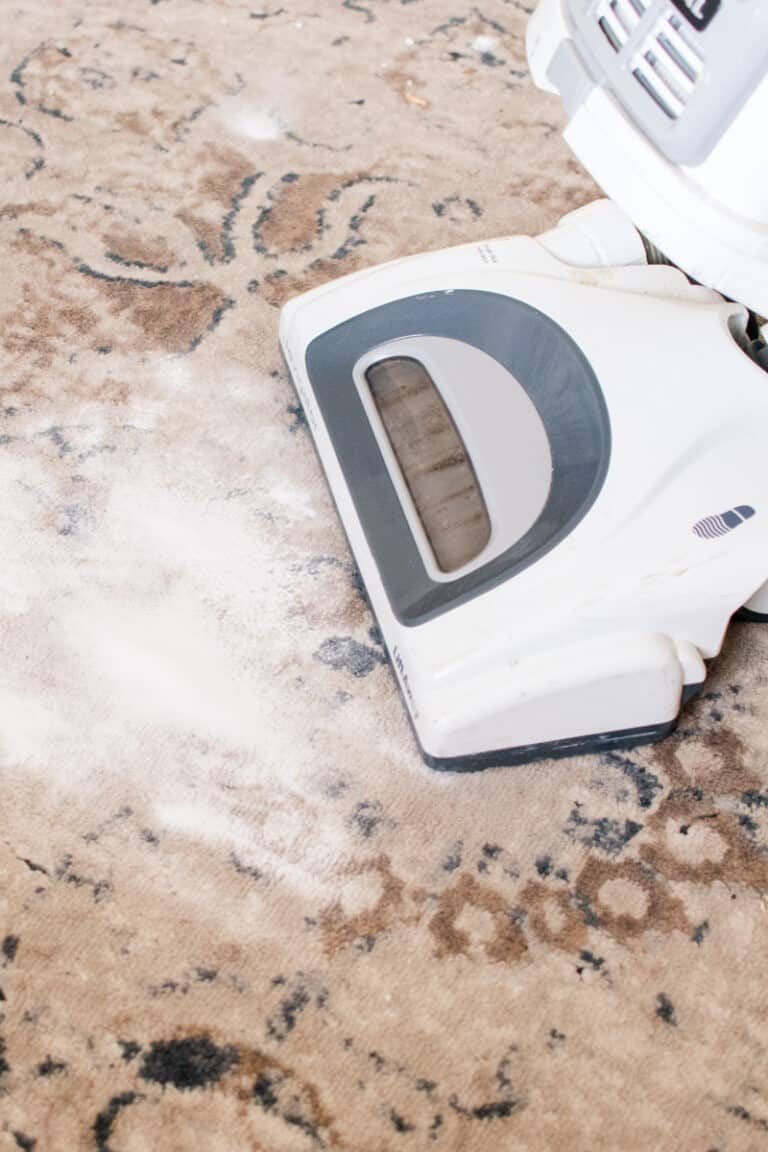 Vacuuming baking soda from a carpet.
