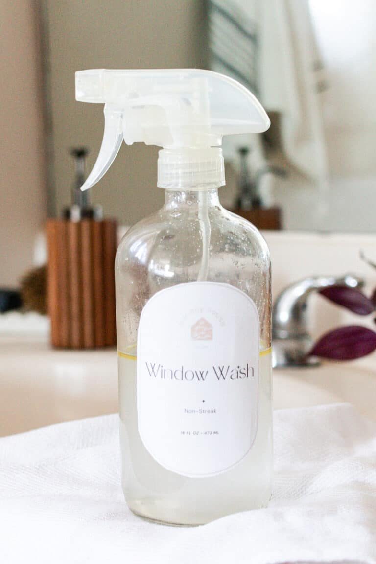 Clear spray bottle with a homemade window cleaning solution on a marble vanity.