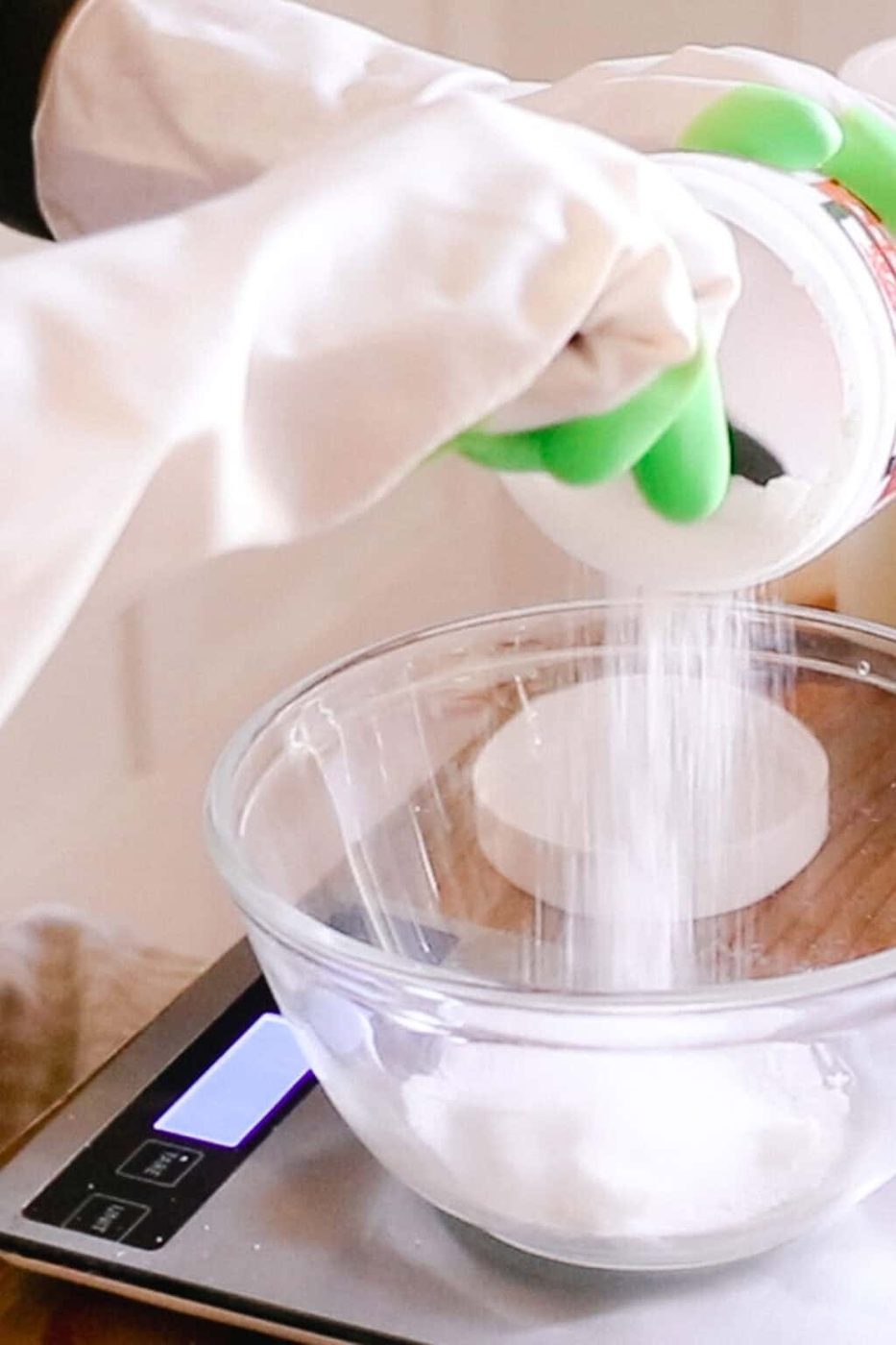 Measuring lye into a glass bowl using a kitchen scale.