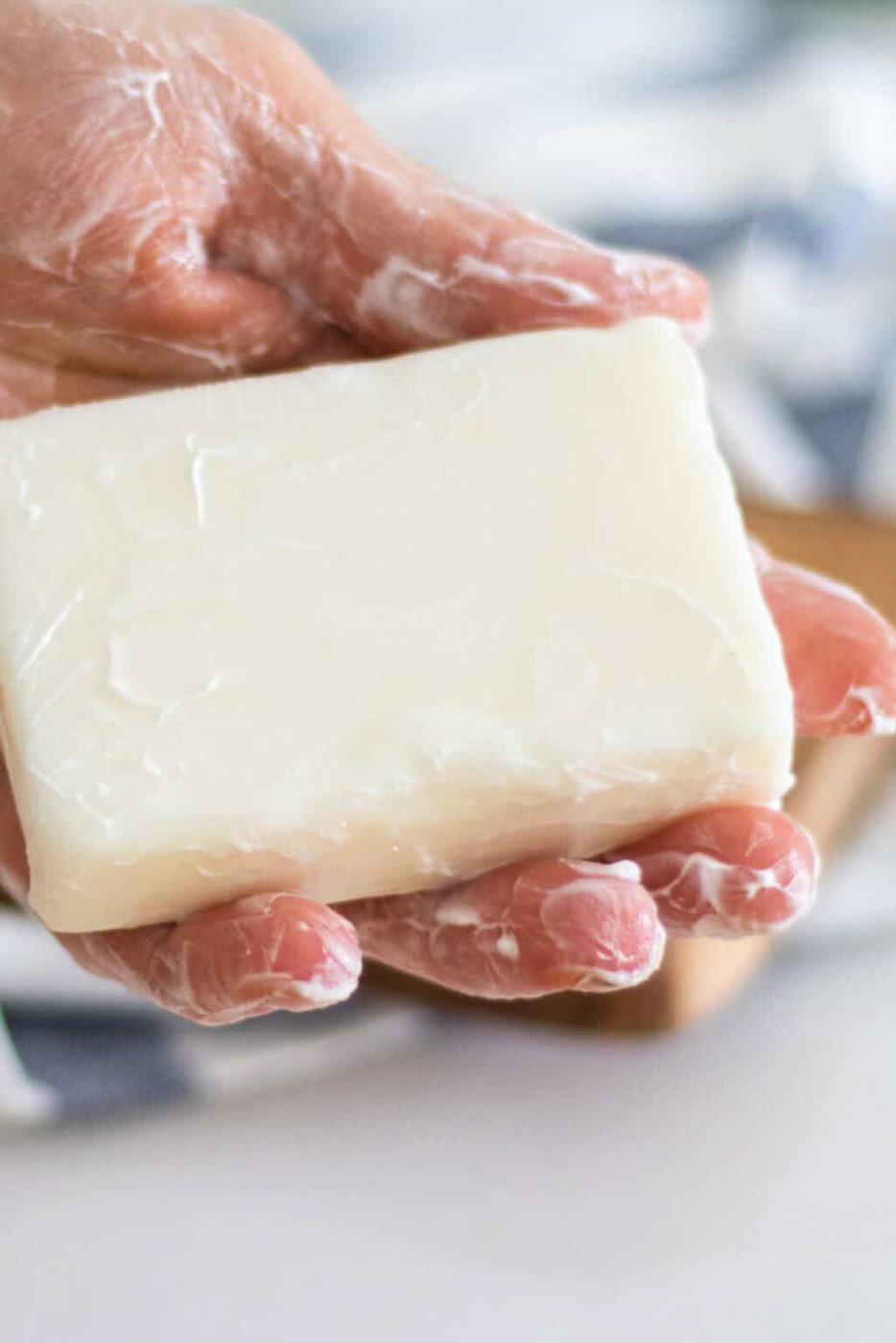 A hand holding a bar of cold process tallow soap.