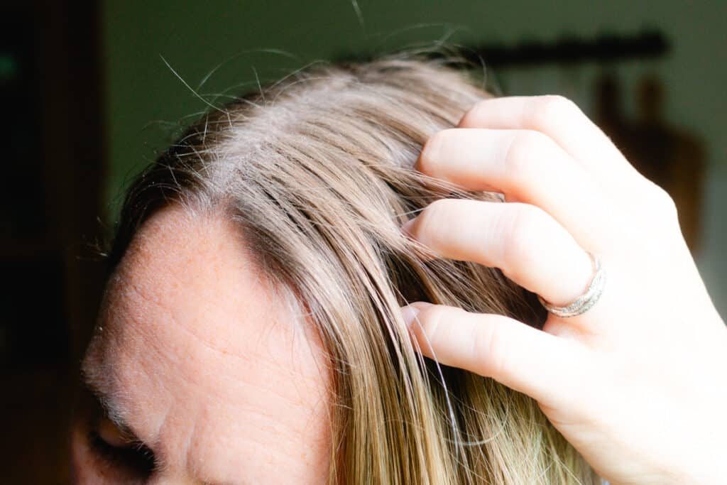 Running the dry shampoo made with cornstarch through our hair with our fingertips.