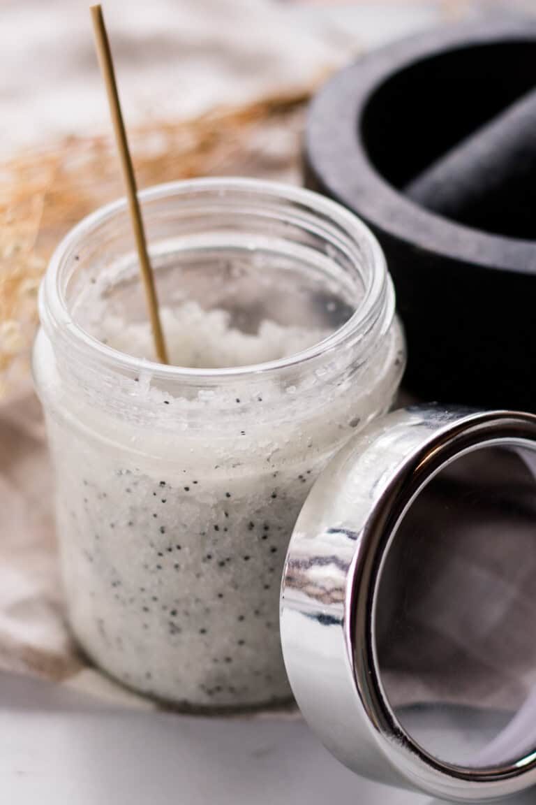 A jar of dead sea salt scrub with dried flowers.