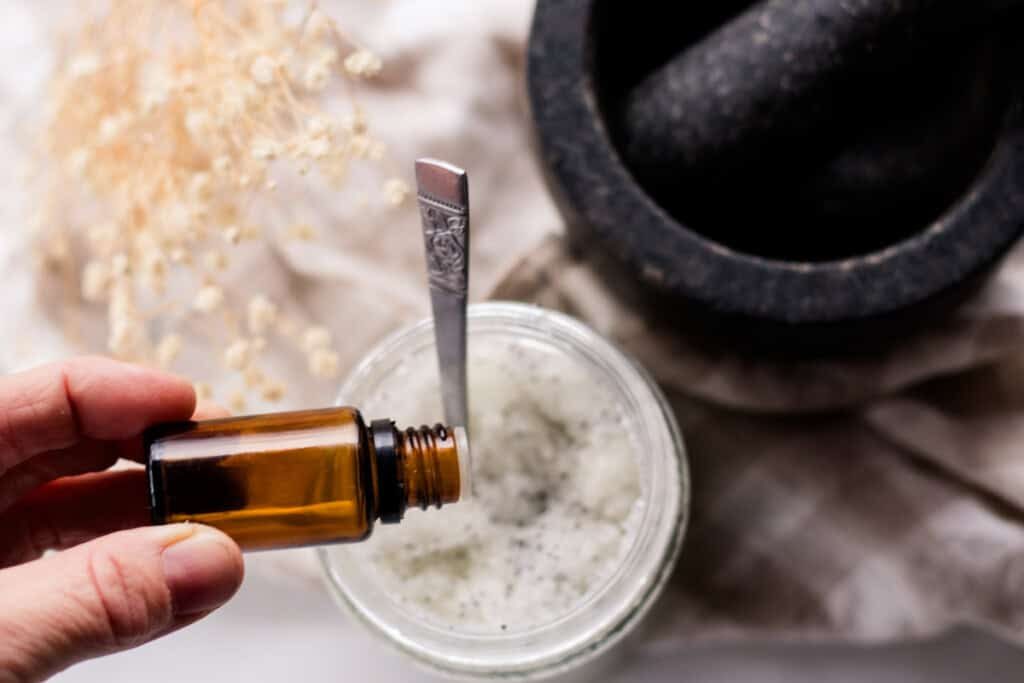 Adding essential oil drops into a jar of sea salt scrub.