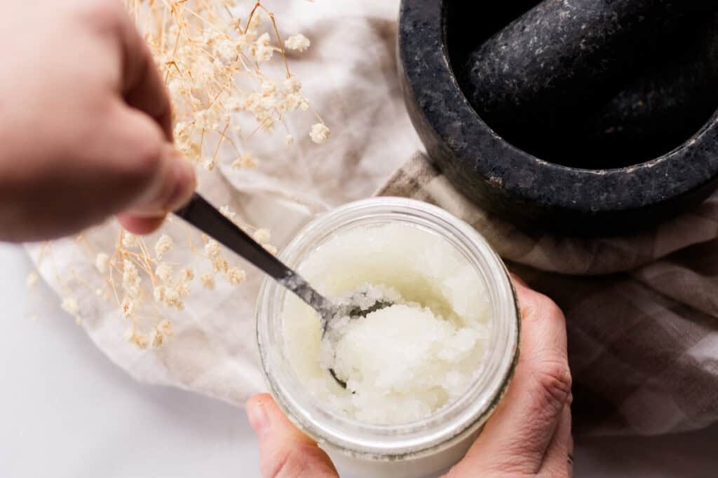 Stirring salt scrub in a glass jar.