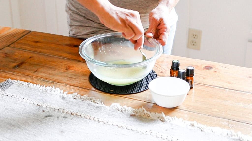 Adding the cornstarch and baking soda to a bowl with melted oils and stirring well.