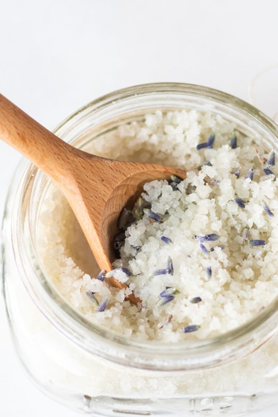 A jar of detoxifying foot bath with a wooden spoon sticking out of it.