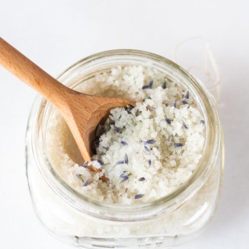 A jar of detoxifying foot bath with a wooden spoon sticking out of it.