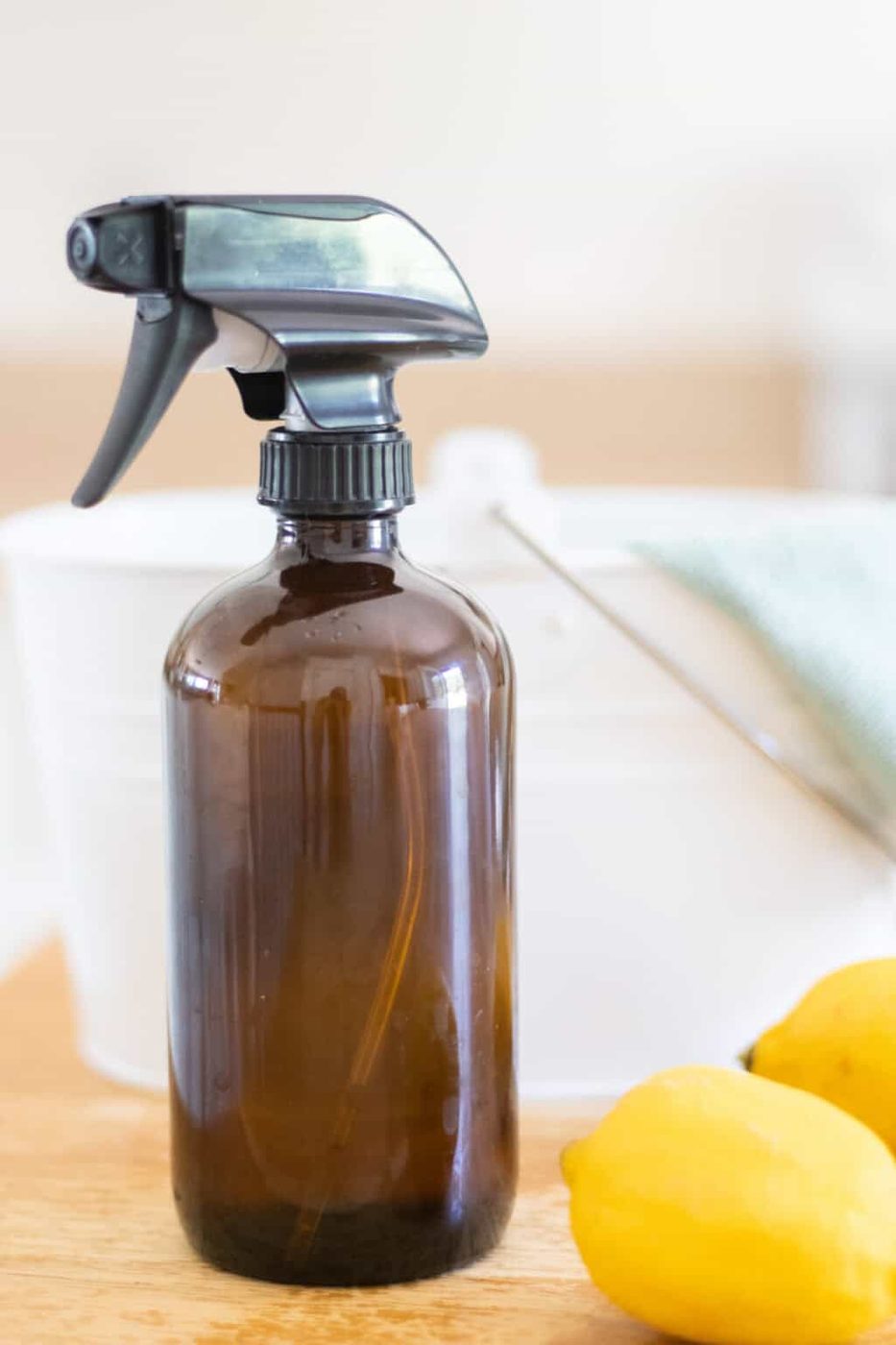 A bottle of all-purpose spray with lemons and a cleaning bucket.