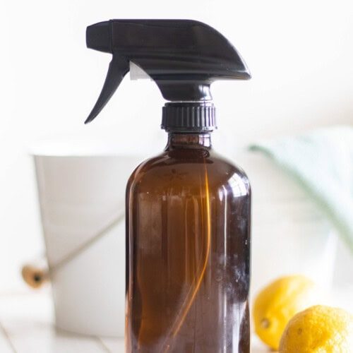 A bottle of all purpose cleaner with a bucket and rag behind it.