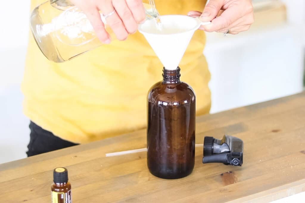 Pouring vinegar into a spray bottle using a funnel.