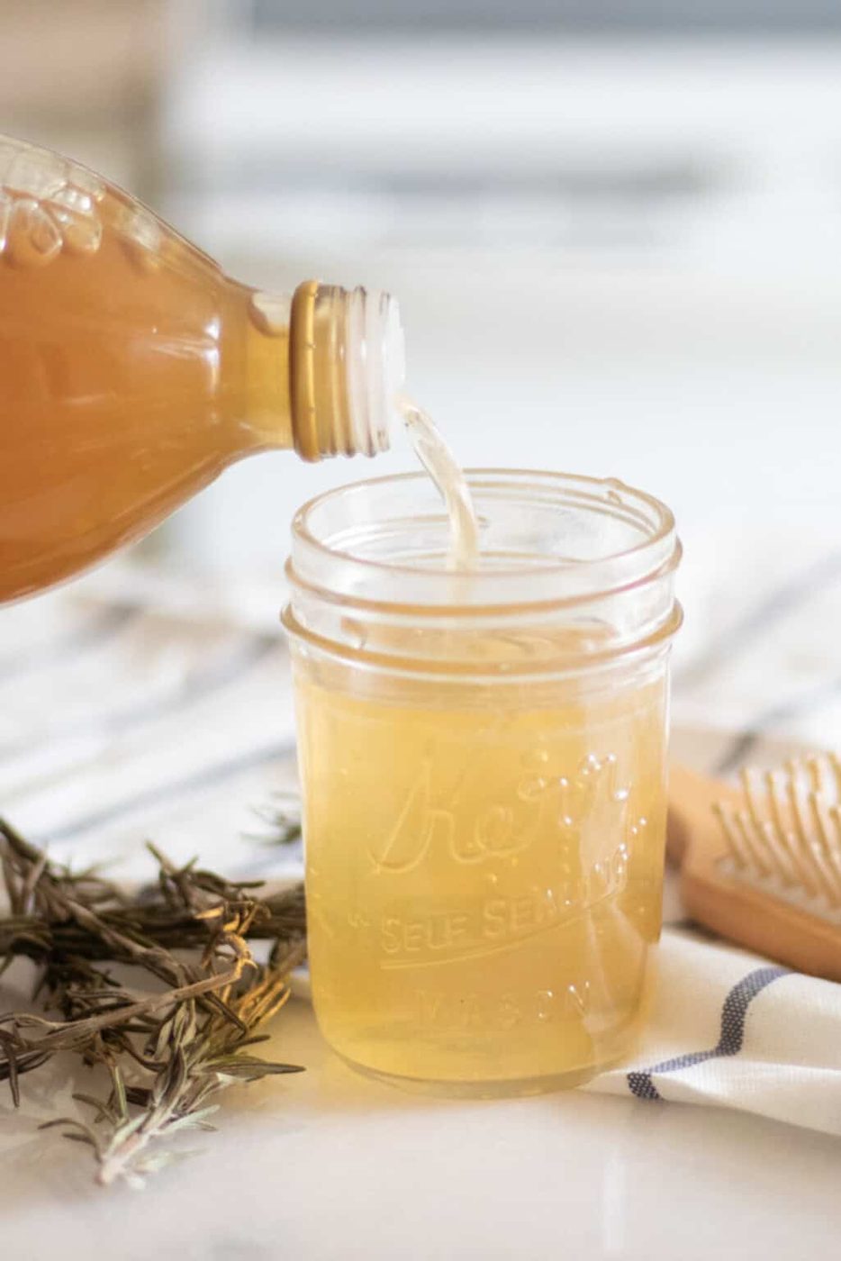 Pouring apple cider vinegar into a small jar.