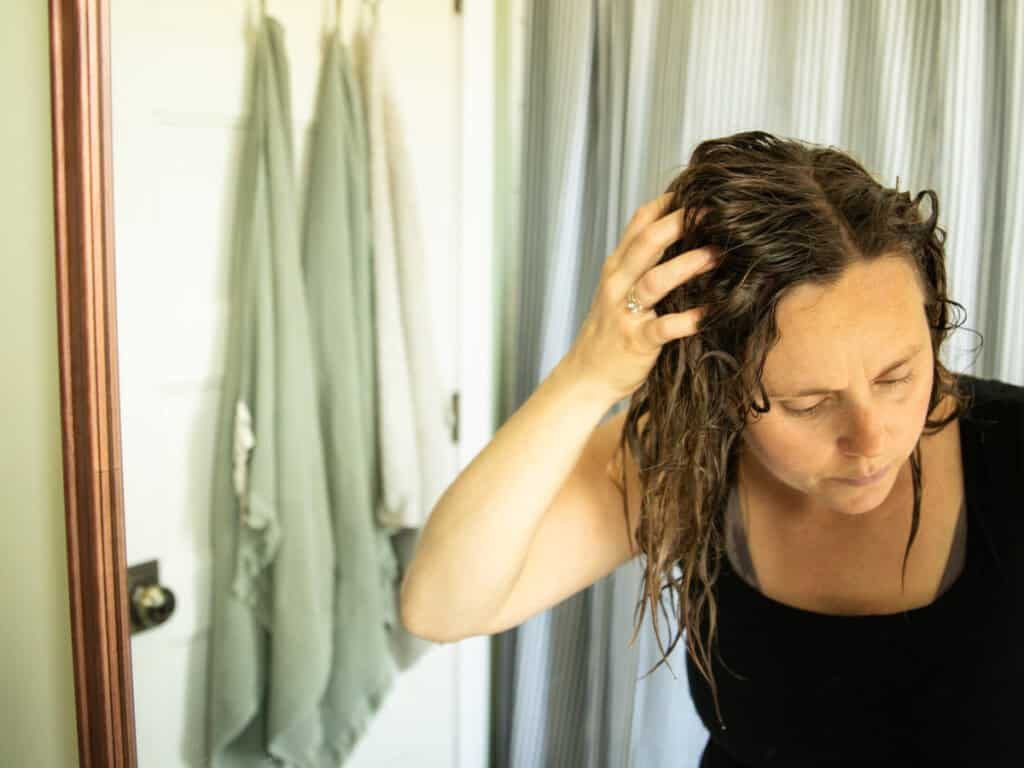 Massaging baking soda rinse into hair in a bathroom.