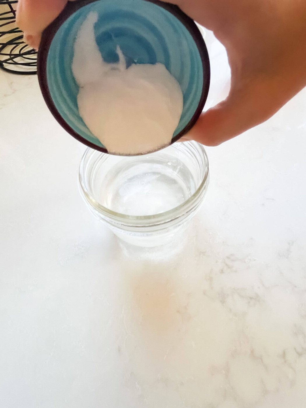 Pouring baking soda into a glass jar of water.