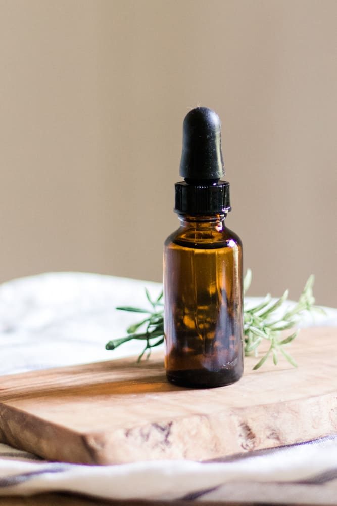 All-natural beard growth and thickening oil for patchy beards in a small dropper bottle on a wooden platform.