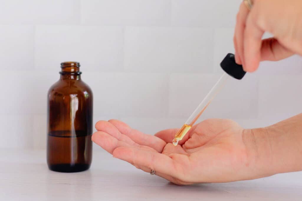 Dropping body oil into the palm to apply it to the skin.