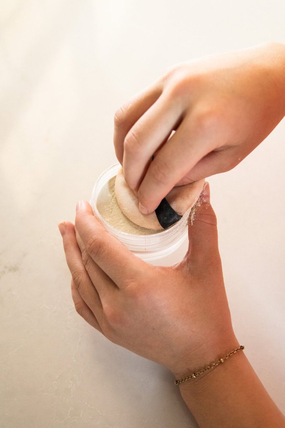Dipping a powder puff in a jar of body powder.