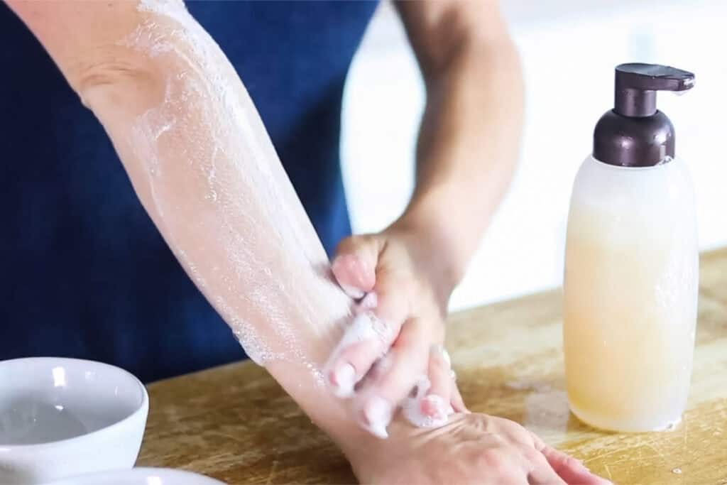 Using homemade natural body wash on the arm with a bottle of the body wash to the side.