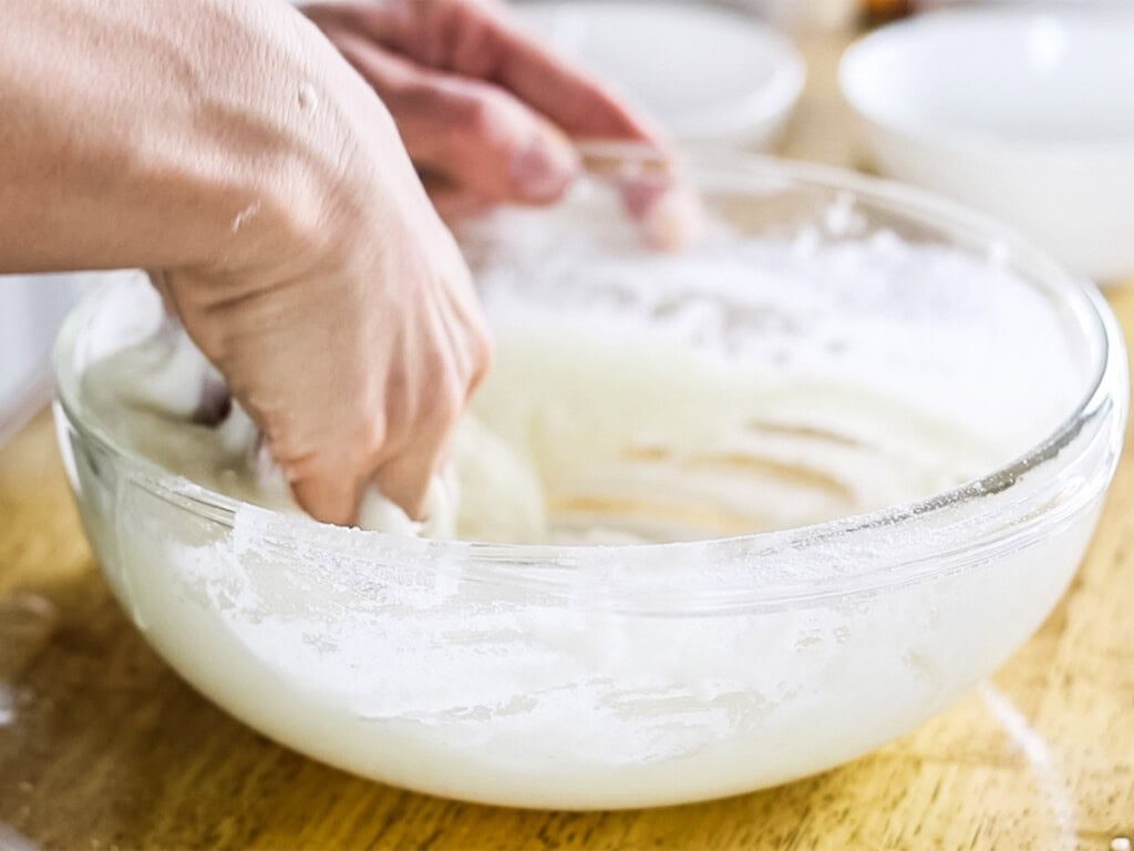 Stirring bubble bath bar ingredients in a bowl with our hands.
