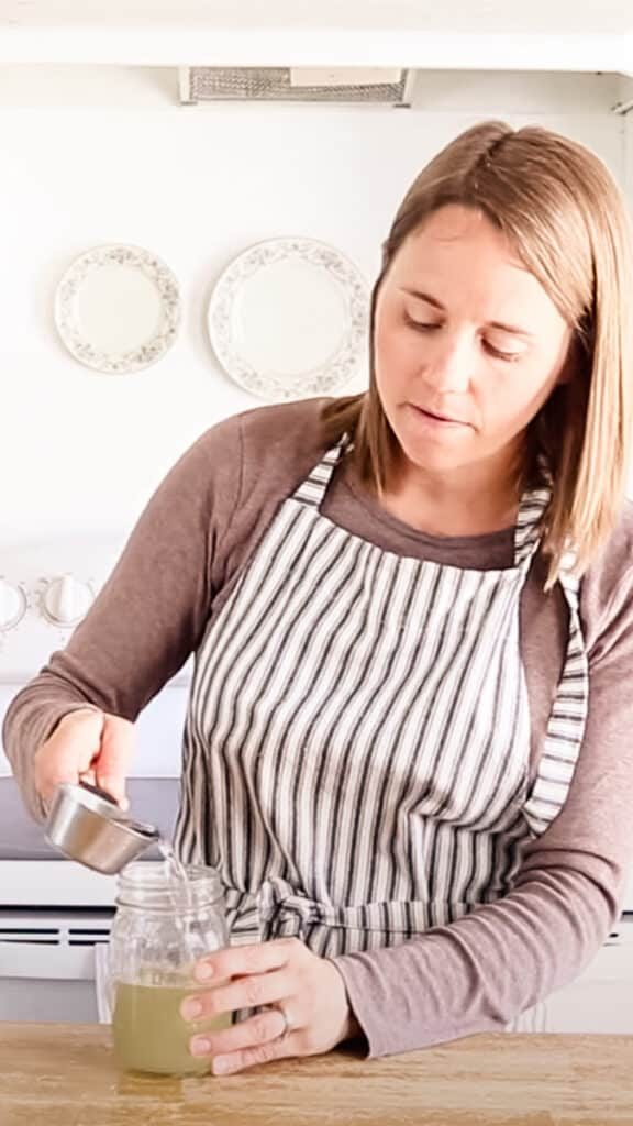 Pouring aloe vera into a mason jar.