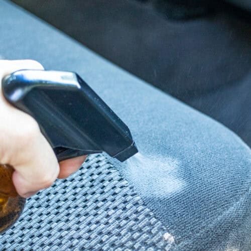 Spraying DIY car seat cleaner on a car seat.
